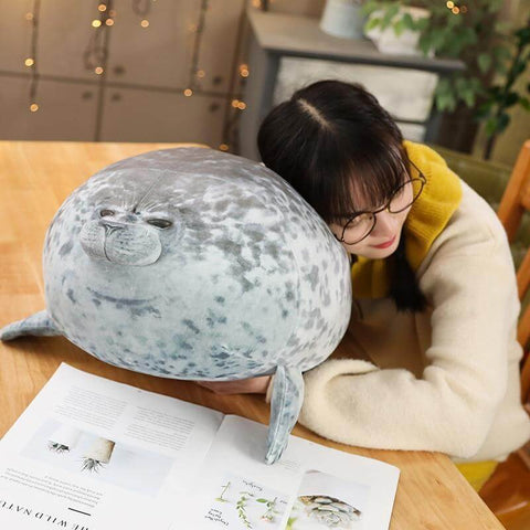 young woman sleeping on cute kawaii chonky seal plushie pillow with realistic print design