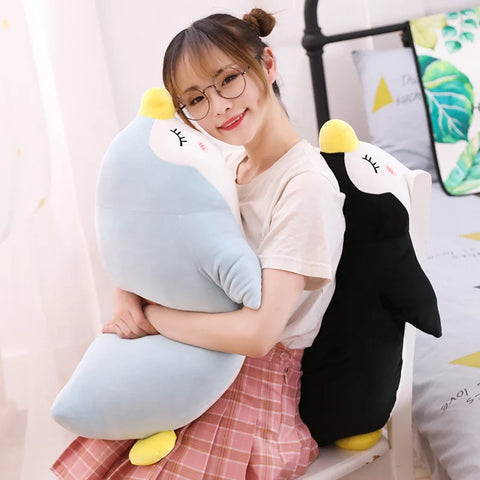 young woman playing with sleepy cute kawaii chonky penguin plushies lying down