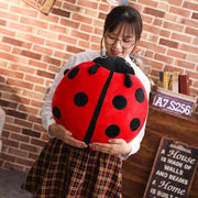 young woman holding cute kawaii chonky soft round mochi ladybug plushie pillow