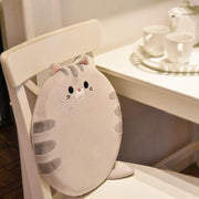 cute kawaii chonky round cat plush pillow cushion with tail and gray fur with stripes sitting on chair