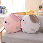pink and white gray cute kawaii chonky soft round bunny rabbit plushie pilow with fluffy floppy ears sitting decoratively on sofa couch bed