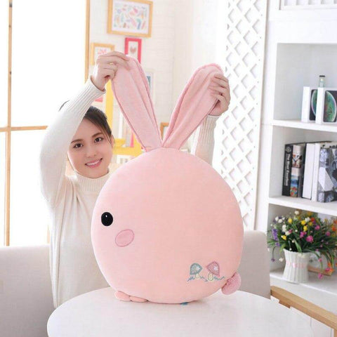 young woman playing with pink cute kawaii chonky soft round bunny rabbit plushie pilow with fluffy floppy ears