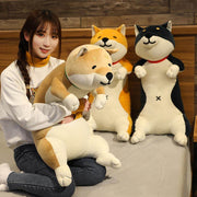 young woman cuddling with big black, brown, and orange cute kawaii chonky shiba inu dog plushies in bed