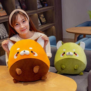 young woman playing with cute chonky orange and green racoon plushies in a living room