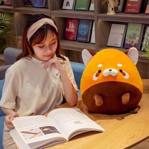 young woman studying next to cute chonky orange racoon plushie