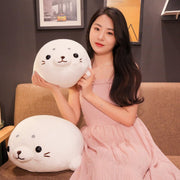young woman playing with white cute kawaii round chonky seal plushies