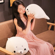 young woman playing with white cute kawaii round chonky seal plushies