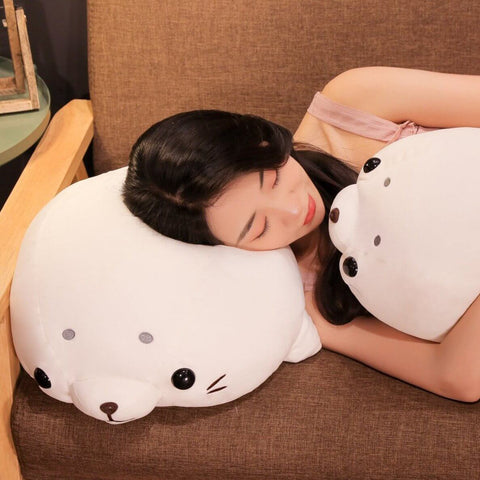 young woman sleeping on white cute kawaii round chonky seal plushies