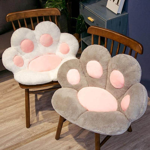 white and gray cute chonky paw pillows sitting on chairs