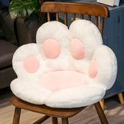 white cute chonky paw pillow with pink toe beans sitting on chair