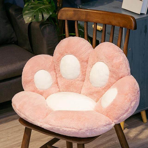 pink cute chonky paw pillow with white toe beans sitting on chair