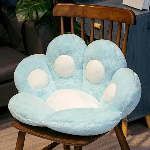 blue cute chonky paw pillow with white toe beans sitting on chair