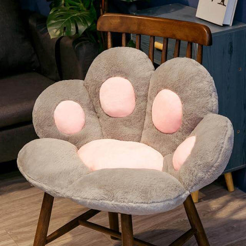 gray cute chonky paw pillow with pink toe beans sitting on chair