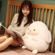 young woman sitting next to fluffy cute kawaii round chonky sheep plushie