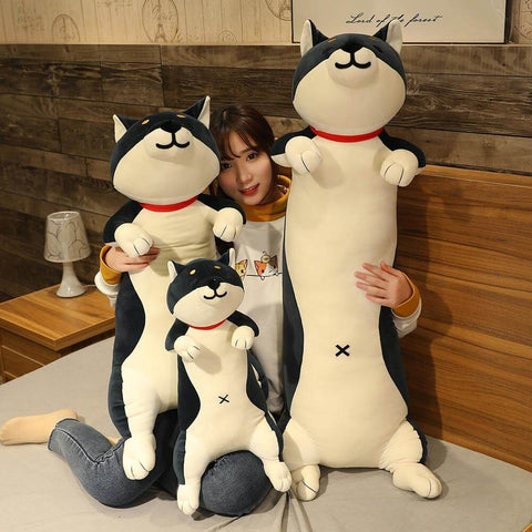 young woman cuddling with big and small black cute kawaii chonky shiba inu dog plushies in bed