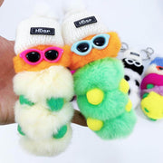 cute kawaii chonky white and green cool caterpillar keyrings with sunglasses, beanie, and sweater on a bag