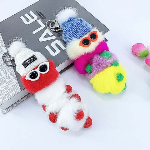 cute kawaii chonky white and rainbow cool caterpillar keyrings with sunglasses, beanie, and sweater on a bag