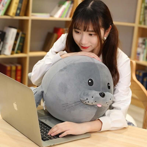young woman cuddling with cute kawaii round chonky seal plushies in gray