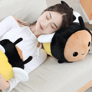 young woman sleeping on cute kawaii chonky bee plushie with wings and black and yellow stripes